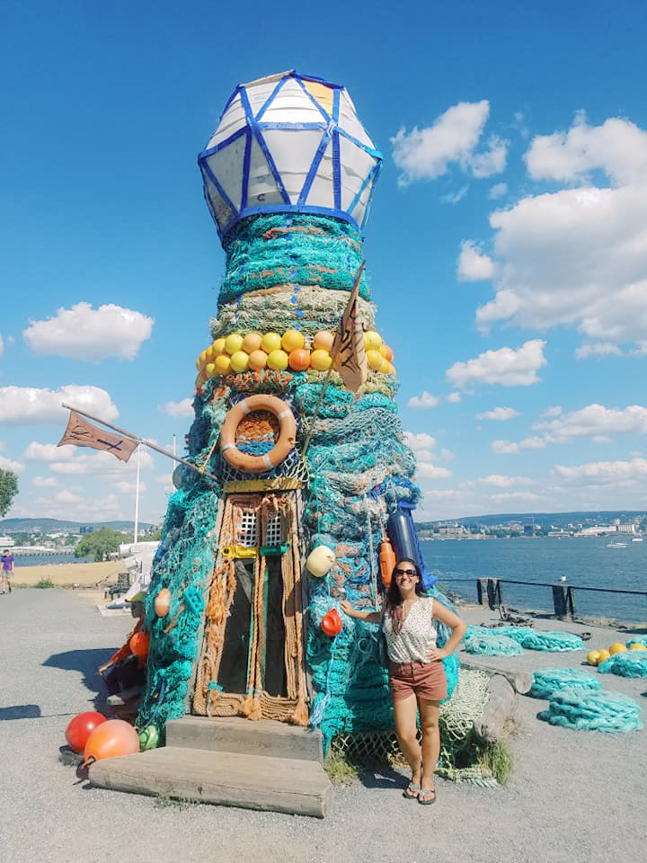 A woman stands besides a lighthouse in Oslo, Norway