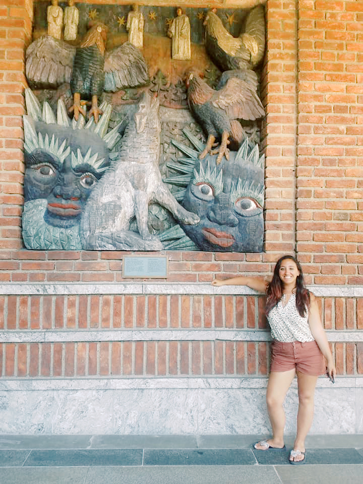 A woman poses beside a mural outside of the Oslo city hall