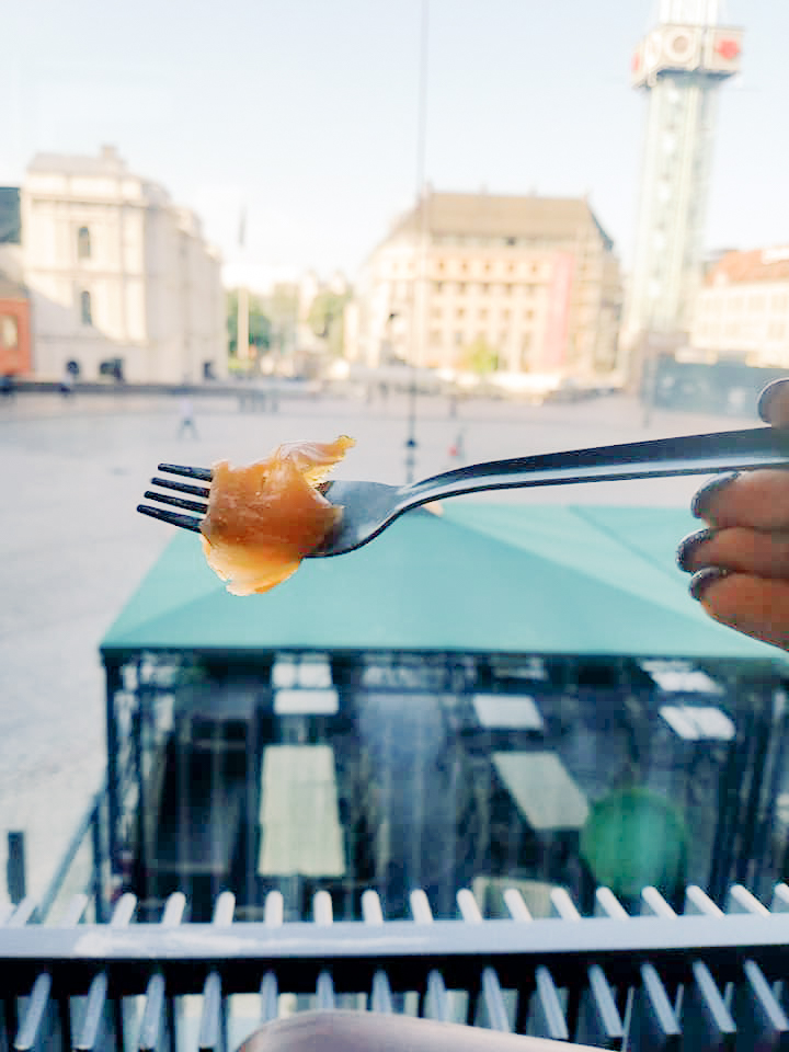 A piece of smoked salmon is held up on a fork at a restaurant