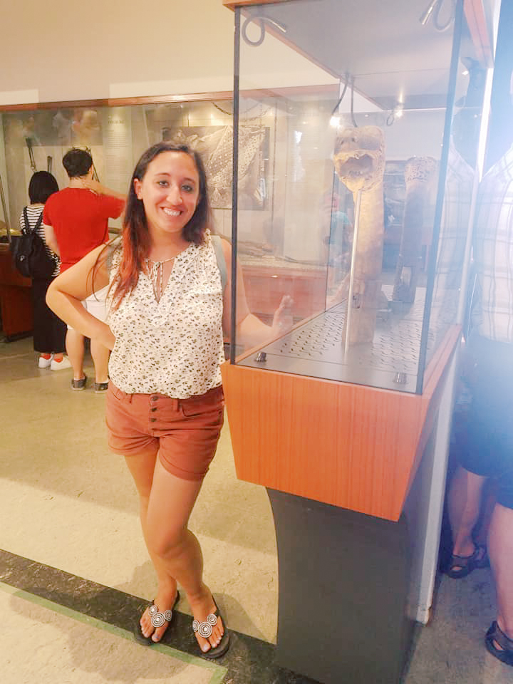 A woman poses next to Viking artifacts on display in a museum 