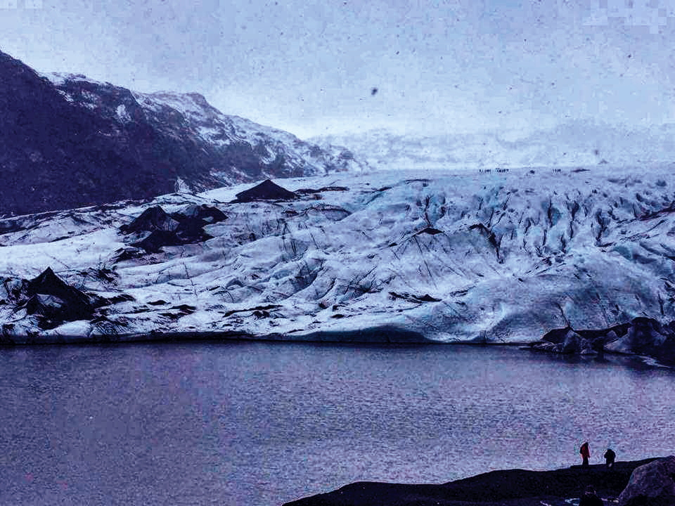 Two people sillouetted against Solheimajokull Glacier