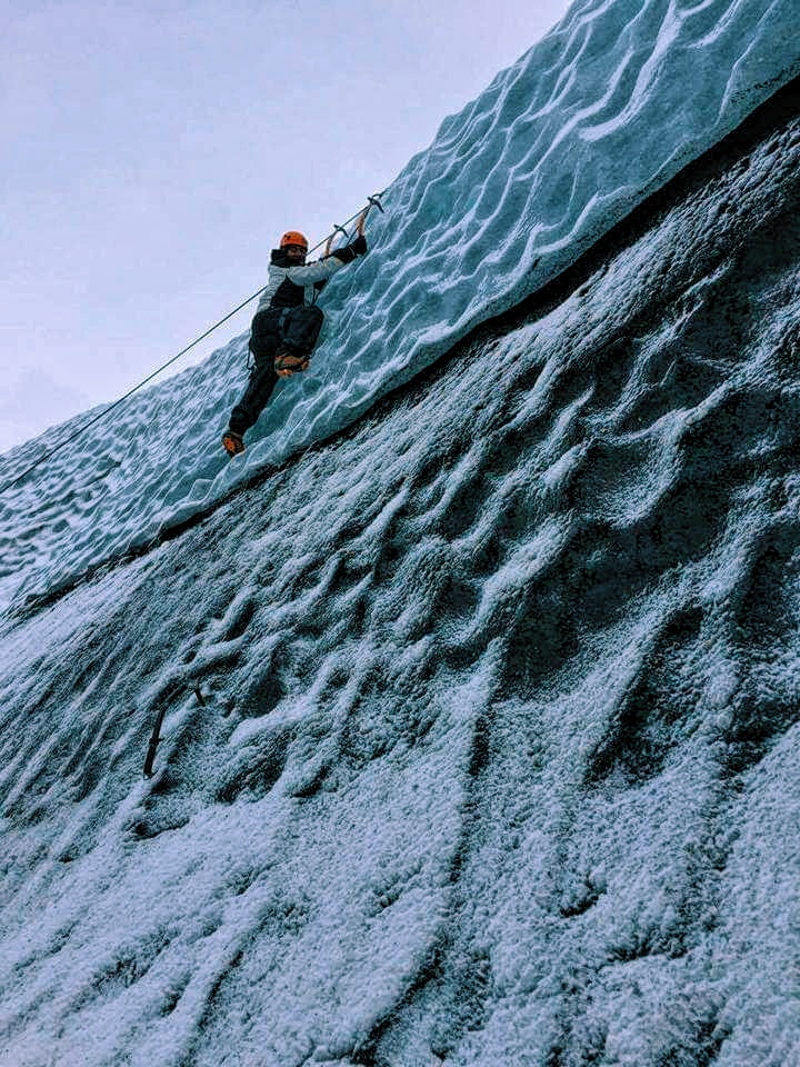 A man scales a wall made of ice in Solheimajokull in Iceland