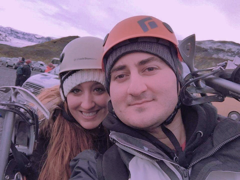 A couple wearing helmets takes a selfie before climbing Solheimajokull in Iceland