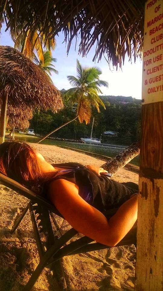 A woman lies in a chair on the beach at sunset in St Lucia